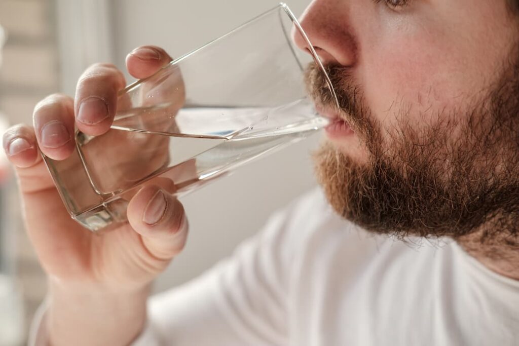 Homem com barba bebendo água